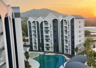 Image of a multi-story residential building with a pool at sunrise/sunset