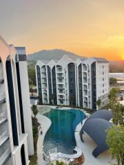 Image of a multi-story residential building with a pool at sunrise/sunset