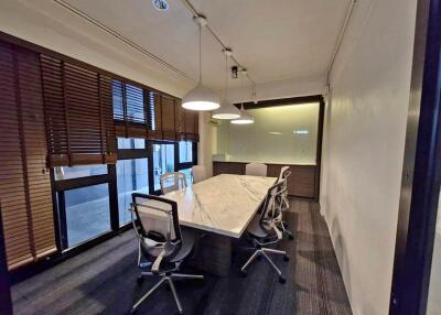 Well-lit conference room with a large marble table, modern chairs, and window blinds