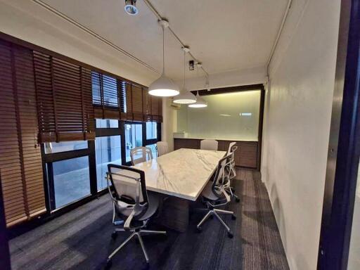 Well-lit conference room with a large marble table, modern chairs, and window blinds