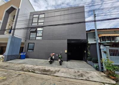 A modern grey 3-story building with two motorcycles parked in front