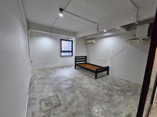 Empty bedroom with concrete floor and single bed frame