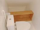 Small bathroom with white toilet and wooden shelf