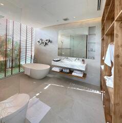 Modern bathroom with white bathtub, floating vanity, large mirror, and wooden shelving