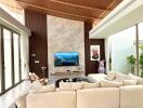 Modern living room with high wooden ceiling, marble accent wall, large sectional sofa, and wall-mounted TV