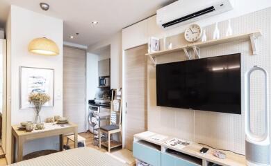 Modern living area with wall-mounted TV, dining table, and air conditioning