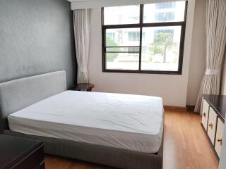 A bedroom with a large window, bed, and light-colored curtains