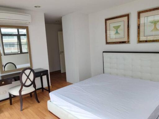 Bedroom with bed, dressing table, chair, and wall decorations