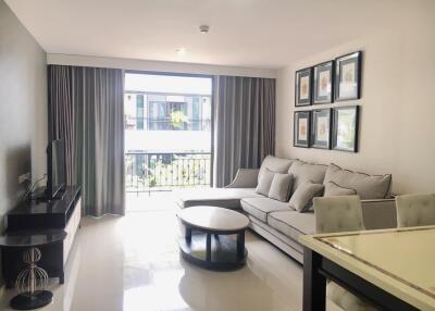 Modern living room with a large window, gray couch, TV, and dining table