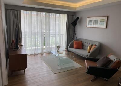 Modern living room with light wooden flooring, grey sofa, and floor-to-ceiling windows with sheer curtains