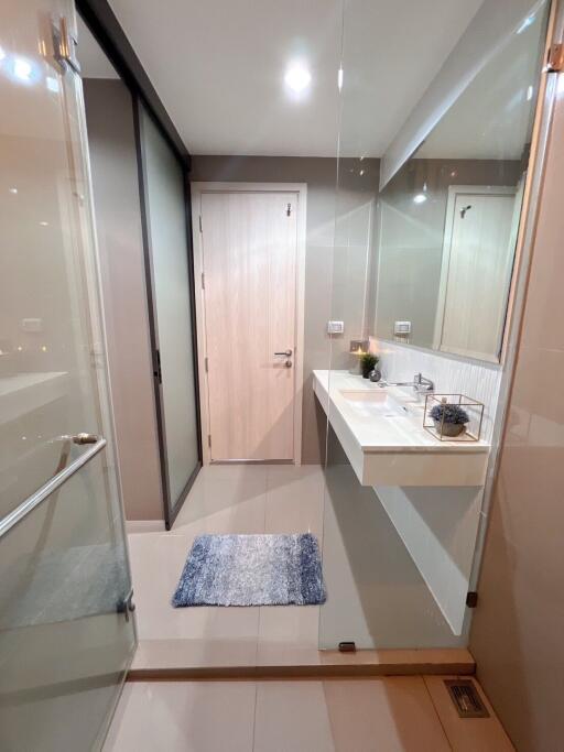 Modern bathroom with glass shower, vanity sink, and grey tile flooring