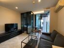 Modern living room with a glass partition, TV unit, black sofa, and small dining area.