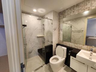 Modern bathroom with tiled walls, glass shower, and white fixtures