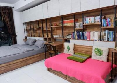 Spacious bedroom with a bed, a sofa, a bookshelf, and wall-mounted cabinets.