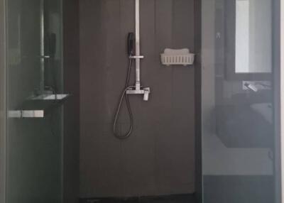 Modern shower area with glass doors and dark tiles