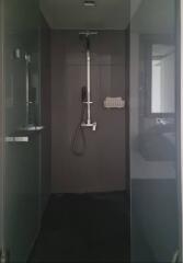 Modern shower area with glass doors and dark tiles