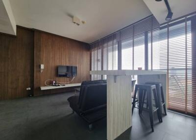 Modern living room with TV, bar counter, and stools