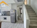 Modern kitchen area with adjacent staircase and fridge