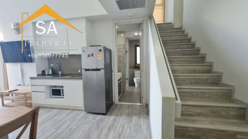 Modern kitchen area with adjacent staircase and fridge