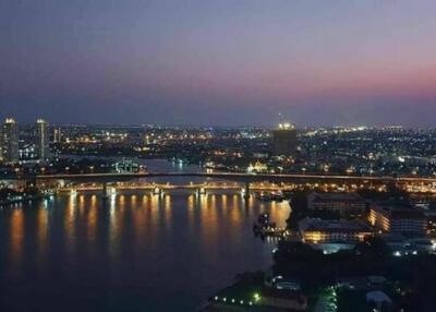 Nighttime city skyline with a river and illuminated buildings