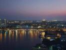 Nighttime city skyline with a river and illuminated buildings