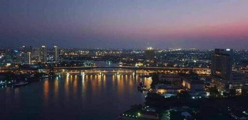 Nighttime city skyline with a river and illuminated buildings