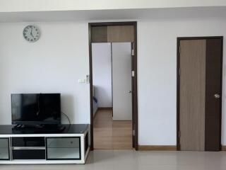 Living room with TV and visible doorway to bedroom