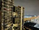 Night view of a modern high-rise apartment building with cityscape in the background