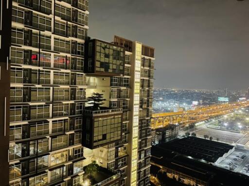 Night view of a modern high-rise apartment building with cityscape in the background