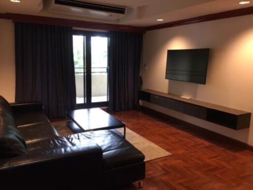 Living room with couch, coffee table, television, and large window with curtains