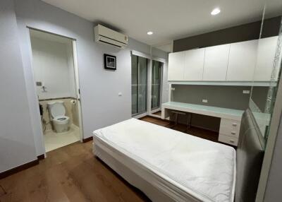 Modern bedroom with attached bathroom, desk, and ample storage.