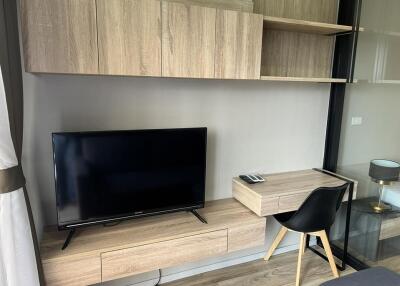 Modern living room with a TV, wall-mounted shelves, and a work desk