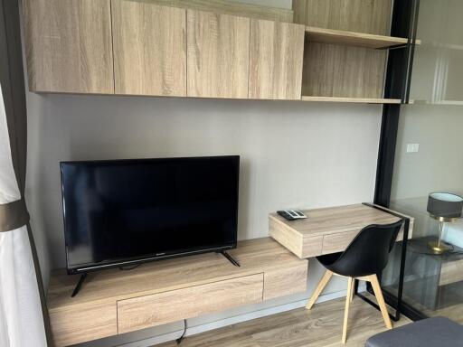 Modern living room with a TV, wall-mounted shelves, and a work desk