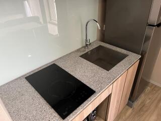 Modern kitchen with granite countertop, induction stove, and stainless steel sink