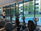 Modern gym with large windows overlooking a pool