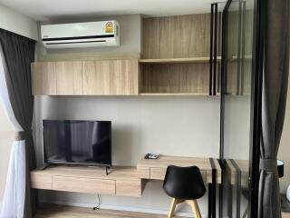 Modern living room with built-in shelves, air conditioner, TV, and study desk