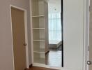 Empty bedroom with built-in shelving and large window