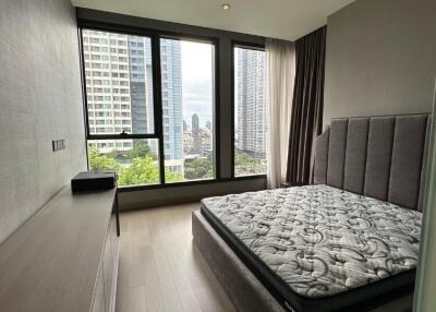 Modern bedroom with large windows and a view of city buildings