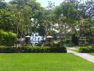 A view of a large outdoor garden area with lush greenery, trees, and an open grassy lawn