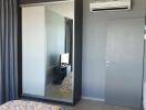 Bedroom with large mirrored wardrobe and air conditioning unit