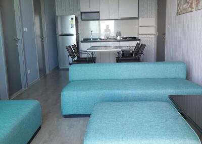 Modern living room with teal sofas and an open plan kitchen