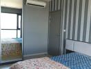 Bedroom with patterned bedspread, mirrored wardrobe, and air conditioning