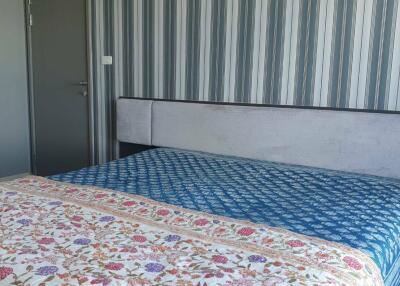 Bedroom with colorful bedspread and striped wallpaper