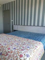 Bedroom with colorful bedspread and striped wallpaper