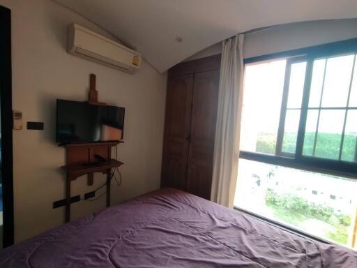 Spacious bedroom with air conditioner, TV, and large window