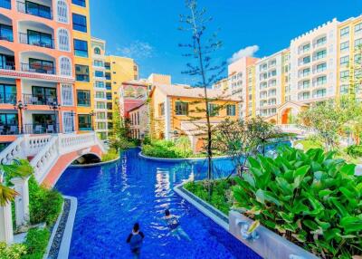 View of residential buildings with a swimming pool and lush landscaping.