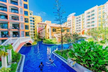 View of residential buildings with a swimming pool and lush landscaping.