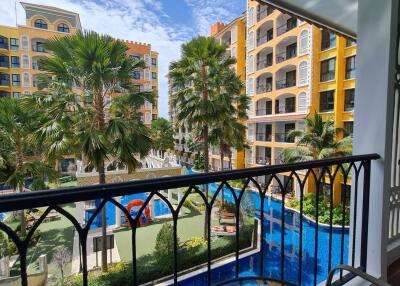 View from balcony overlooking residential complex with pool and palm trees