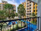 View from balcony overlooking residential complex with pool and palm trees