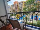 A balcony overlooking an outdoor space with a colorful building and a playground featuring a slide and a pool